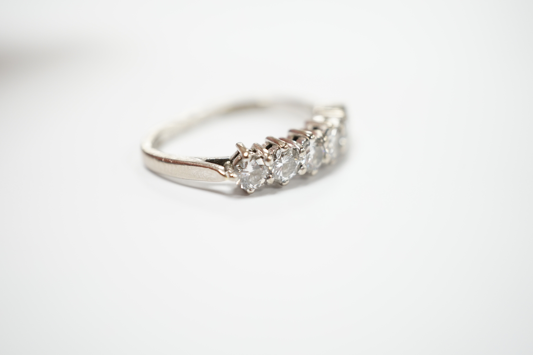 A modern 18ct white gold and six stone diamond set half hoop ring, (shank slightly crushed), gross weight 3.4 grams.